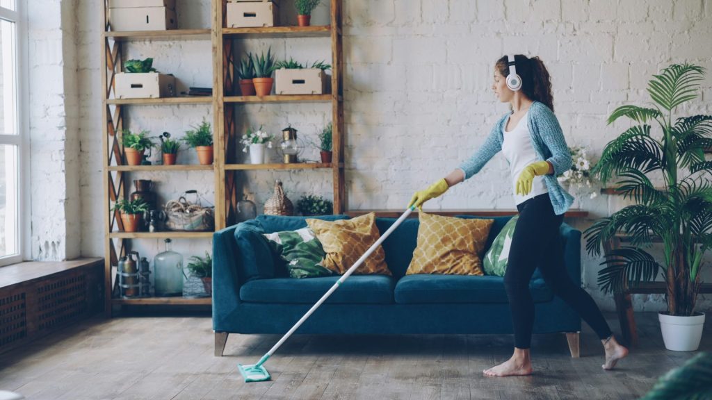 Woman with headphones mopping a wooden floor